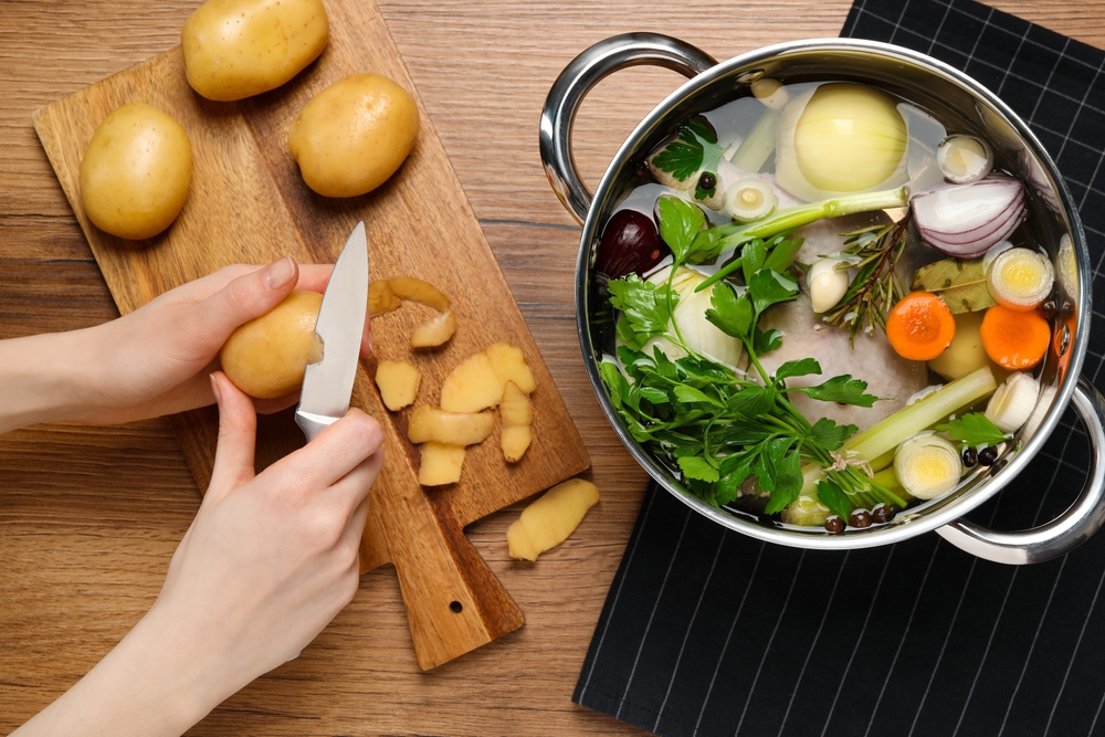 Woman,Peeling,Potato,For,Cooking,Tasty,Bouillon,At,Wooden,Table,